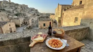 Piatti tipici lucani su un tavolo con vista sui Sassi di Matera al tramonto